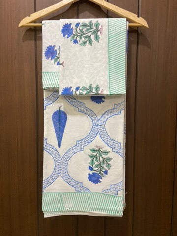 Set of patterned bedsheet hanging on a wooden hanger against a wooden background