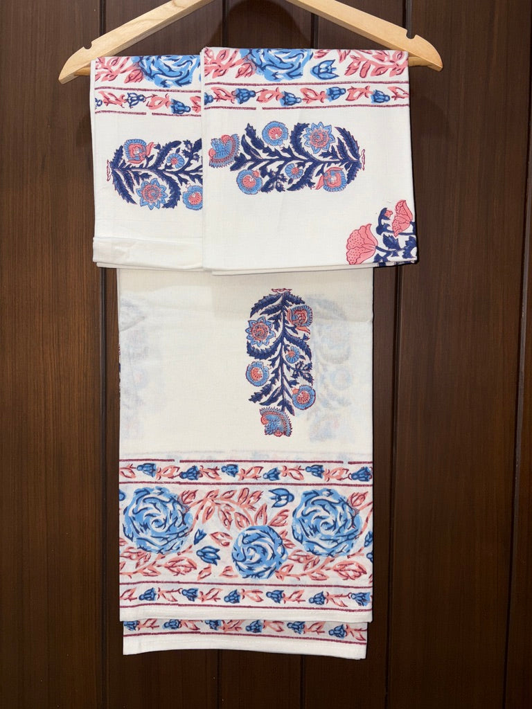 Bedsheet with blue and red floral patterns hanging on a wooden hanger against a wooden background.