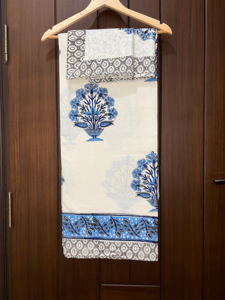 Decorative fabric with blue floral patterns hanging on a wooden hanger against a wooden door.