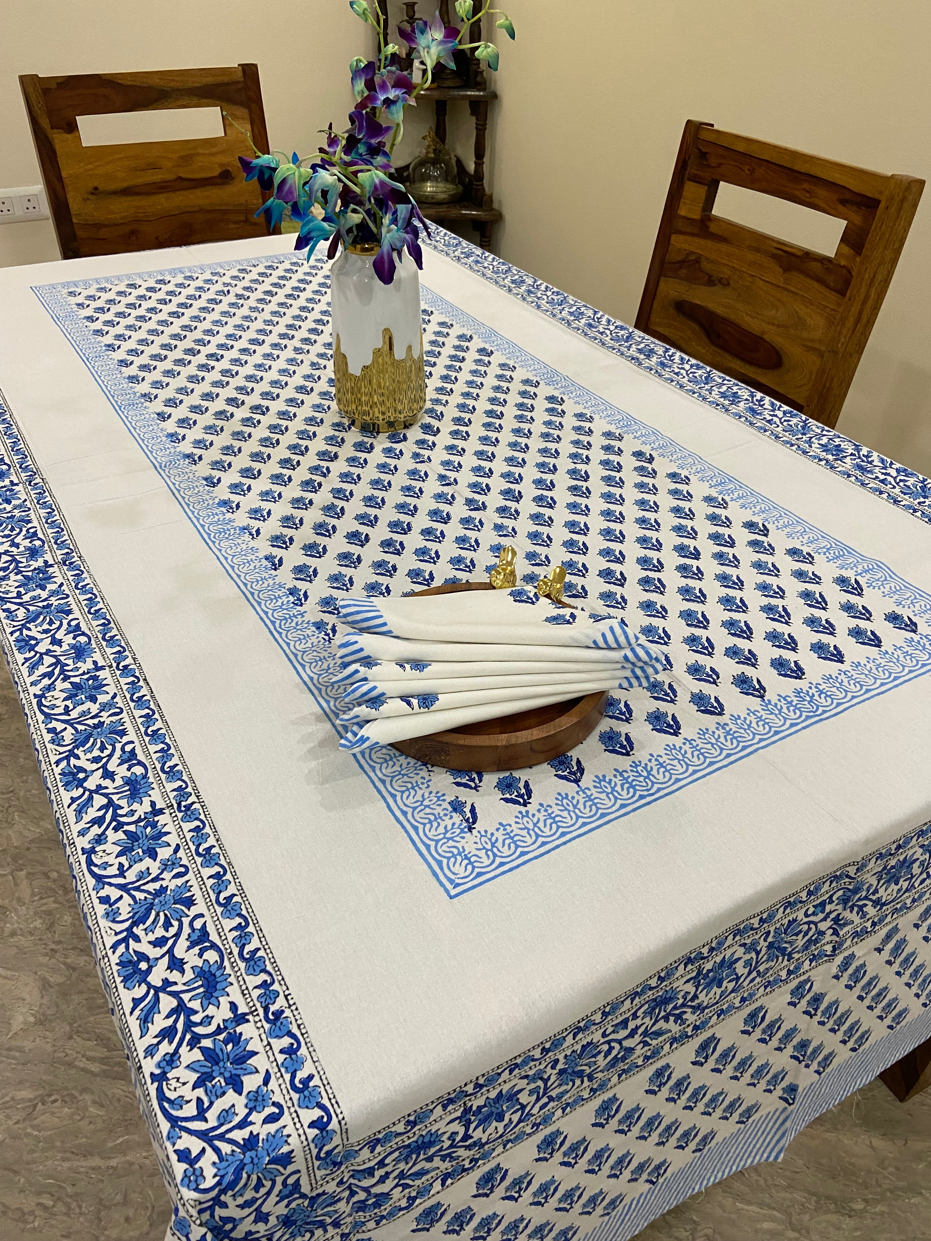 Decorative blue and white patterned tablecloth on a table with a wooden frame and floral decorations.